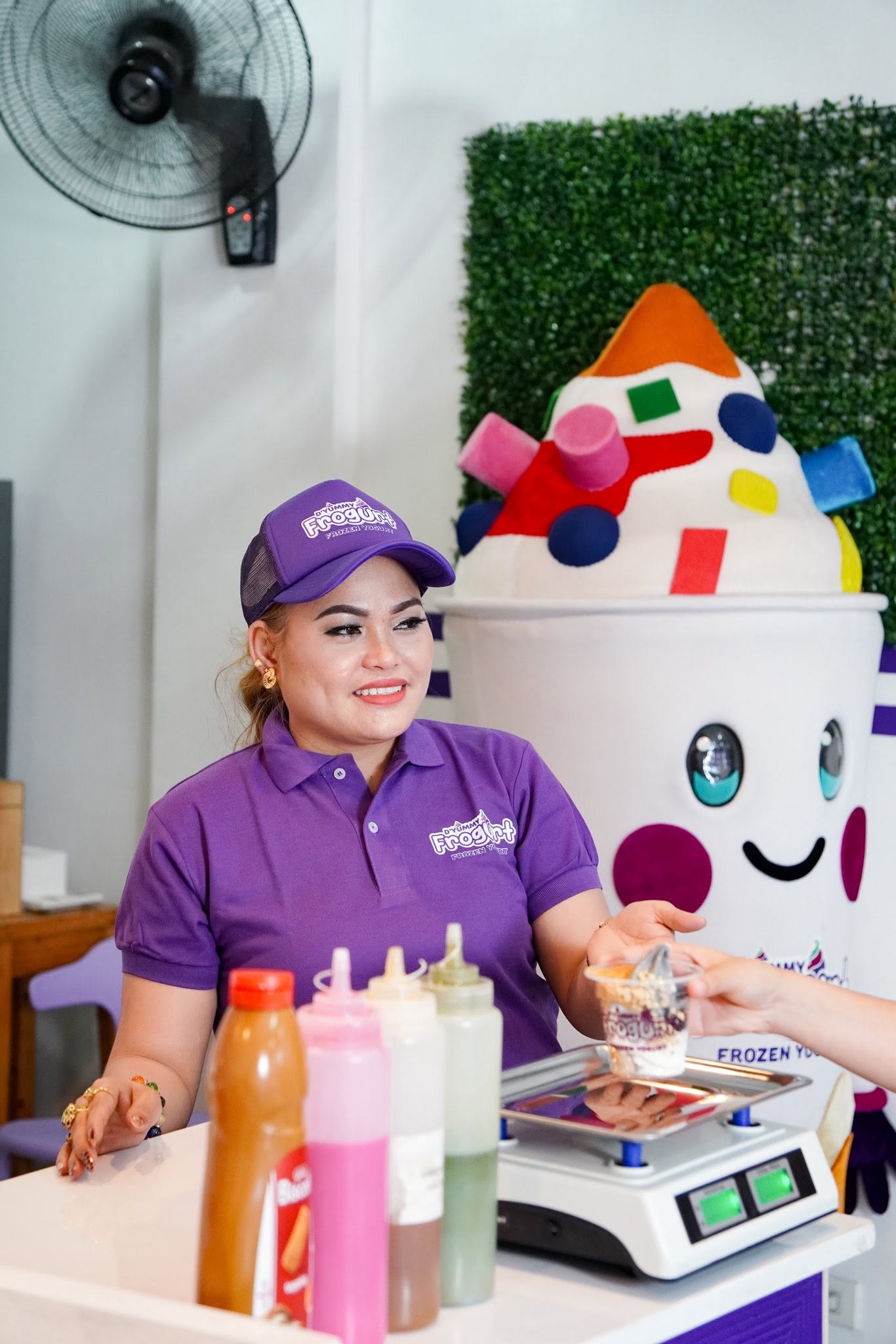 Sonia Nallatan Sendon in D'Yummy Frogurt uniform beside the brand mascot